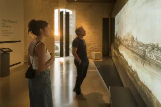 Visitors absorbed in an interactive art installation inside a softly lit modern museum space, golden light creating a warm and contemplative atmosphere.